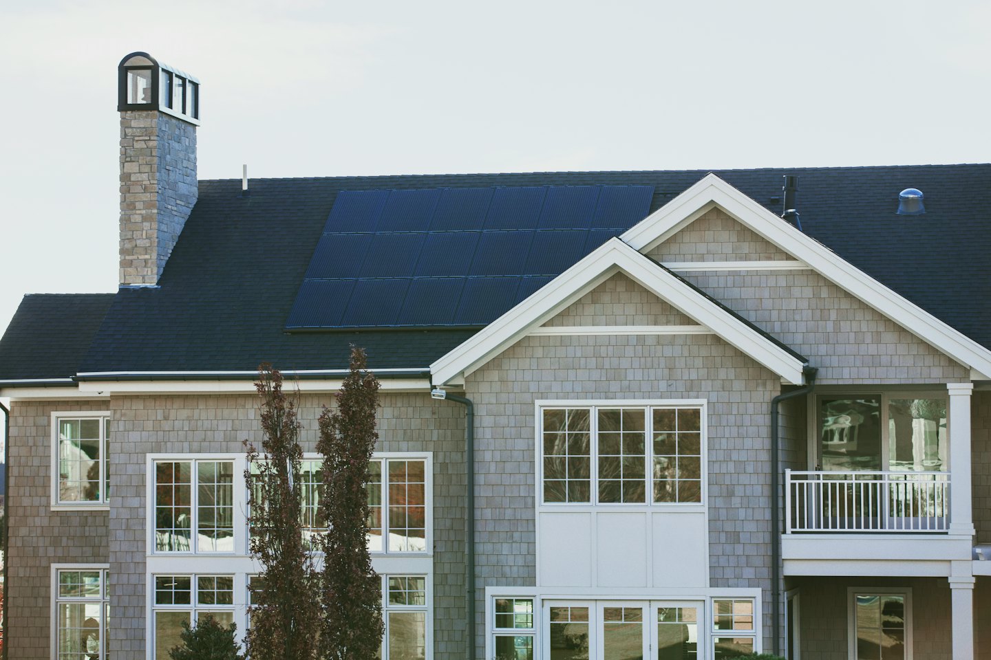 Modern grey shingle house with solar panels on roof.