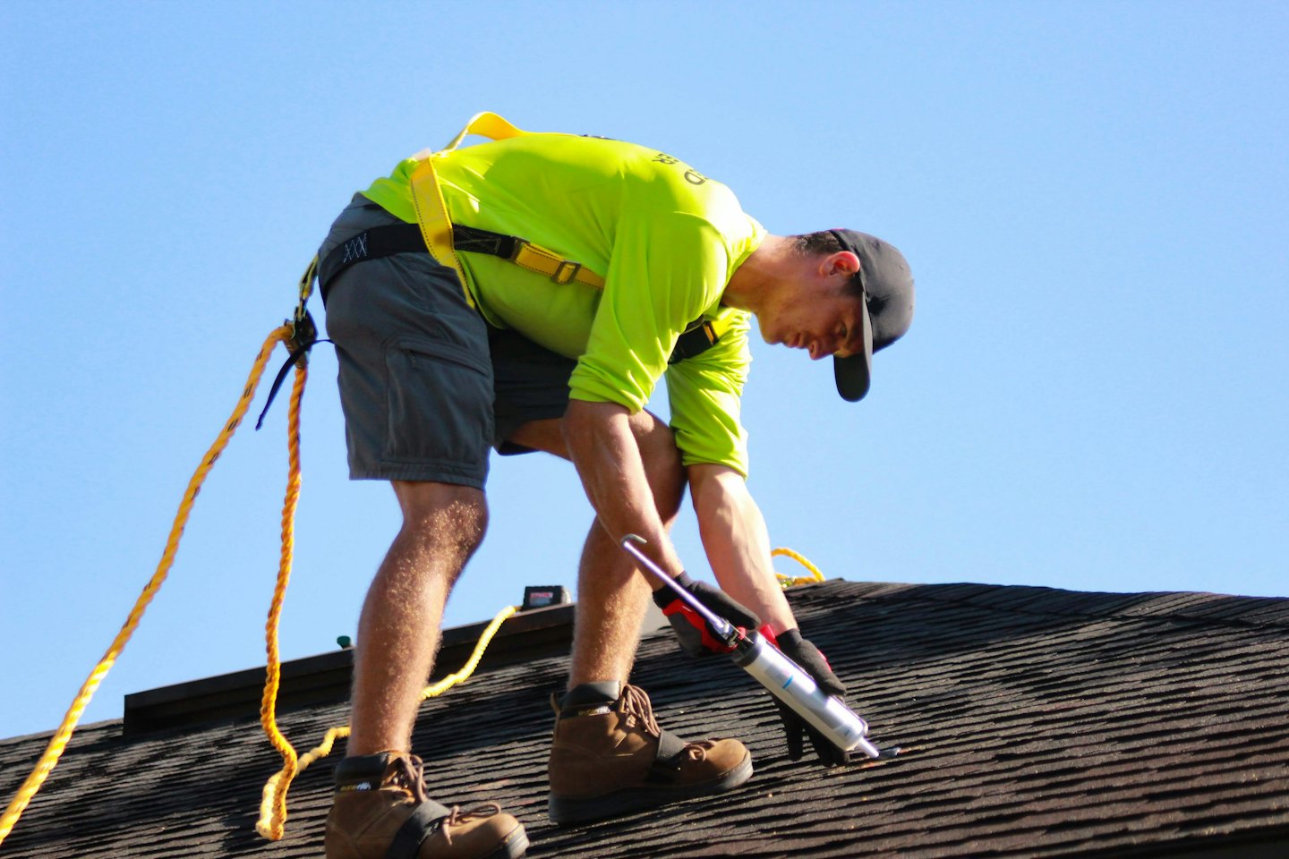 Roofer applying sealant to a shingled roof.